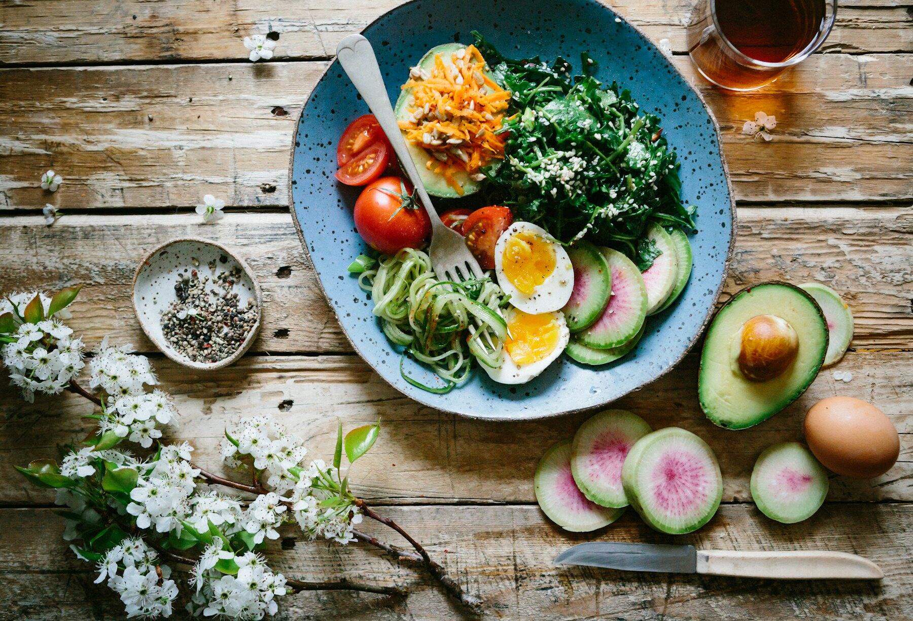 A bowl of fresh vegetables on a wooden table